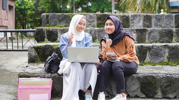 Zwei asiatische Studentinnen, die mit ok Geste diskutieren