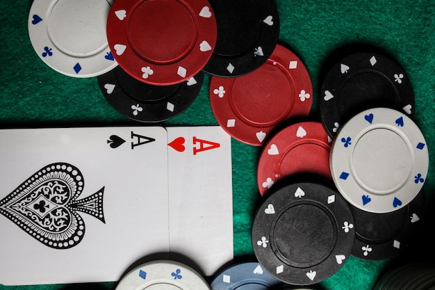 zwei Asse auf dem grünen Spieltisch. zwei Spielkarten und Pokerchips auf einem grünen Casino-Tisch.