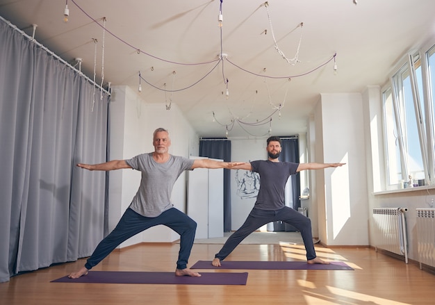 Zwei athletische kaukasische Männer, die während des Trainings in einem Fitnessstudio barfuß auf den Matten stehen