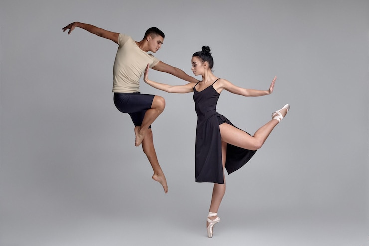 Foto zwei athletische moderne balletttänzer posieren vor einem grauen studiohintergrund.