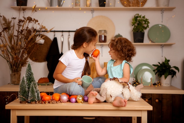 zwei Babys, die Mandarinen in der Weihnachtsküche essen