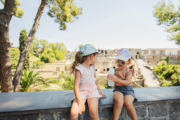 Zwei Babyschwestern, die gegen Panoramablick auf die antike Stadt Pompeji sitzen