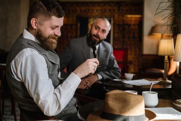 Zwei bärtige Männer in altmodischen Anzügen unterhalten sich oder diskutieren etwas im Restaurant