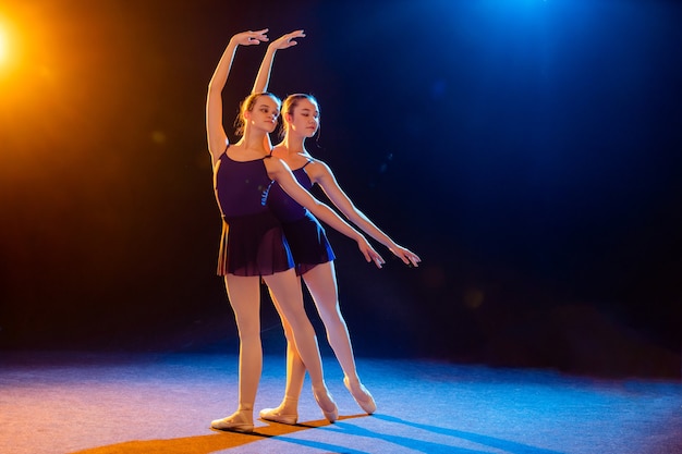 Zwei Ballerinas im schwarzen Kleid posieren beleuchtet von bunten Scheinwerfern