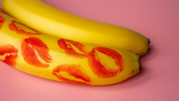 Zwei Bananen mit Spuren von rotem Lippenstift auf rosa Hintergrund, Konzept der Liebe