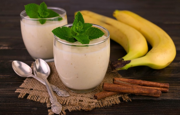 Zwei Bananendesserts mit Zimt in Gläsern auf dunklem Holzhintergrund