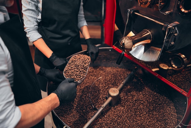 Zwei Baristas genießen das Aroma von verbrannten Bohnen, während sie sie auf dem Spatel halten Industriekonzept Zugeschnittenes Bild