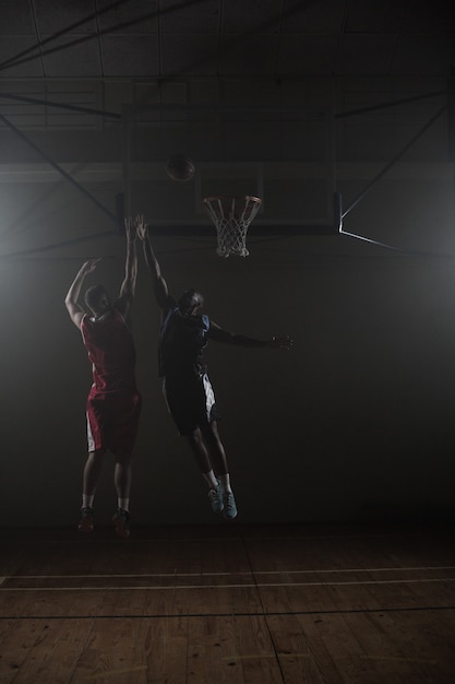 Zwei Basketballspieler: ein Schießen, ein Springen