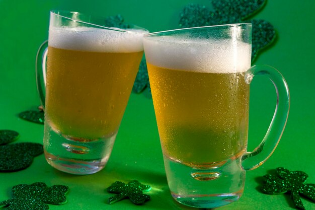 Zwei Becher kaltes Bier auf grünem Hintergrund mit Shamrock und Hut, von oben, St Patrick's Day