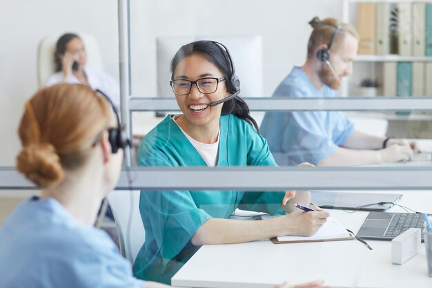 Zwei Bediener in Kopfhörern sprechen und lachen am Tisch während ihrer Arbeit im Call Center