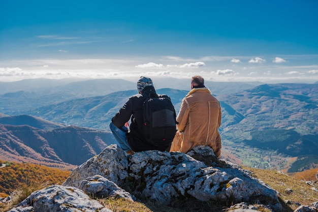 Zwei befreundete Wanderer genießen einen Pausenblick auf die Spitze des Berges