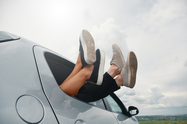 Zwei Beine mit Turnschuhen aus dem Autofenster