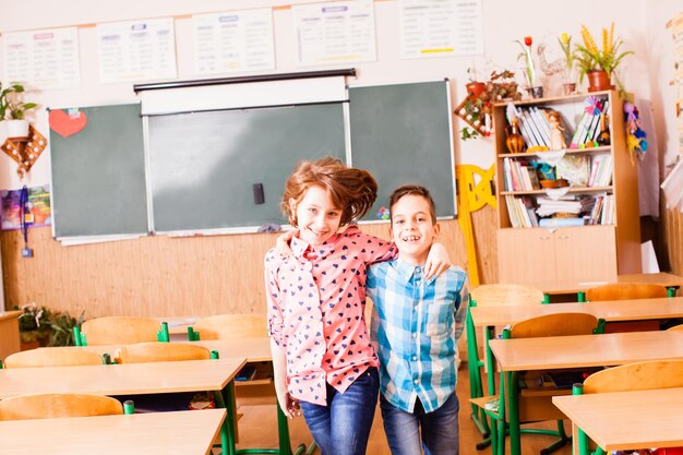 Zwei beste Freunde, die sich umarmen und Spaß haben, im Klassenzimmer zu lächeln