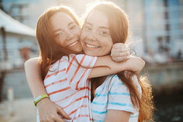 Zwei beste Freunde und Ingwerzwillinge umarmen sich und freuen sich, die beste Zeit des Lebens zusammen zu verbringen Schwesternschafts- und Freundschaftskonzept