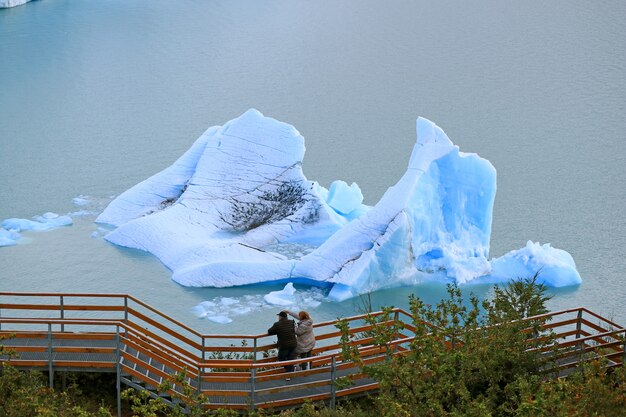 Zwei Besucher am Aussichtsbalkon vor dem riesigen Eisberg am Lake Agentino, El Calafate, Argentinien