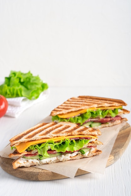 Zwei Bio-Sandwiches mit Schinken-Käse-Salat und geröstetem Brot, serviert auf Schneidebrett in der Küche