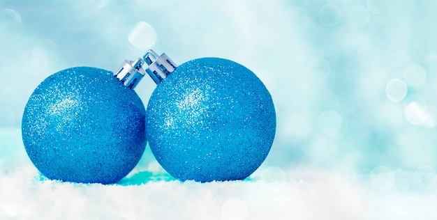 Foto zwei blaue weihnachtsdekorationen im schnee auf einem defokussierten blauen hintergrund mit bokeh