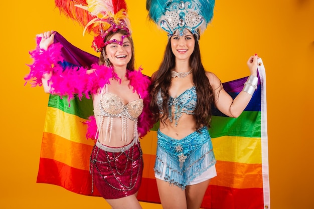 Zwei brasilianische freundinnen in karnevalsoutfits mit lgb-flagge