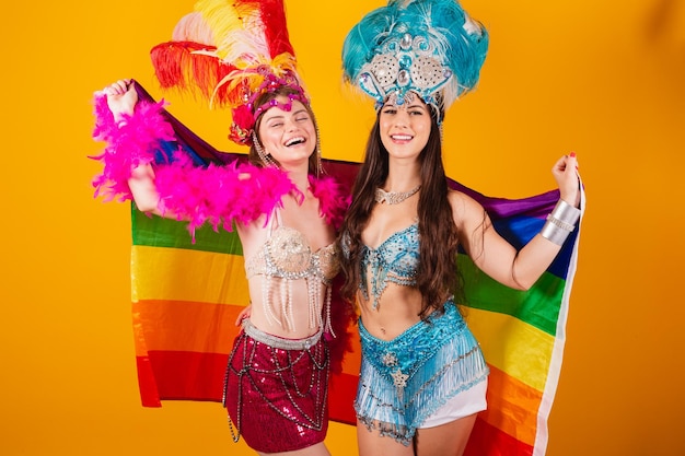 Zwei brasilianische freundinnen in karnevalsoutfits mit lgb-flagge