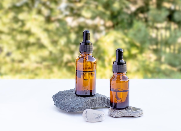 Zwei braune Flaschen ätherisches Öl-Essenz-Serum für die Hautpflege von Frauen auf natürlichem Hintergrund Steinpodium Vorderansicht