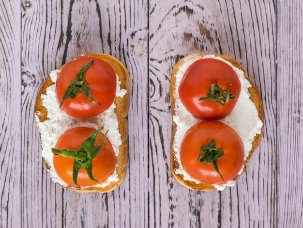 Foto zwei brote hüttenkäse und tomatenhälften auf einem rosa tisch.