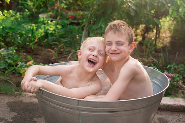 Zwei Brüder, die draußen im Becken baden und lachen. Wochenende im Dorf