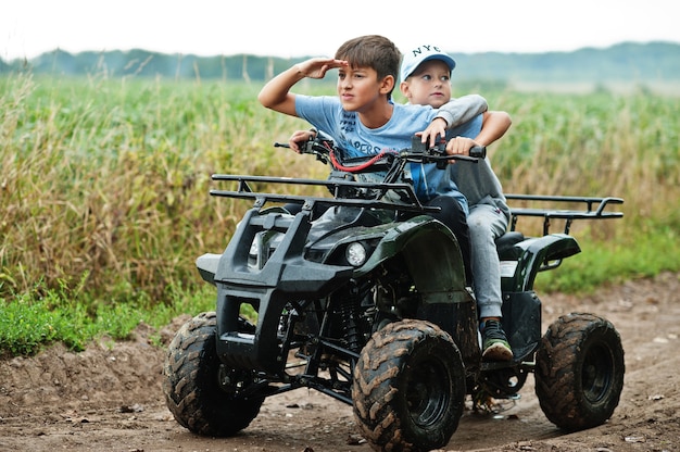 Zwei Brüder, die ein vierrädriges ATV-Quad-Bike fahren. Glückliche Kindermomente.