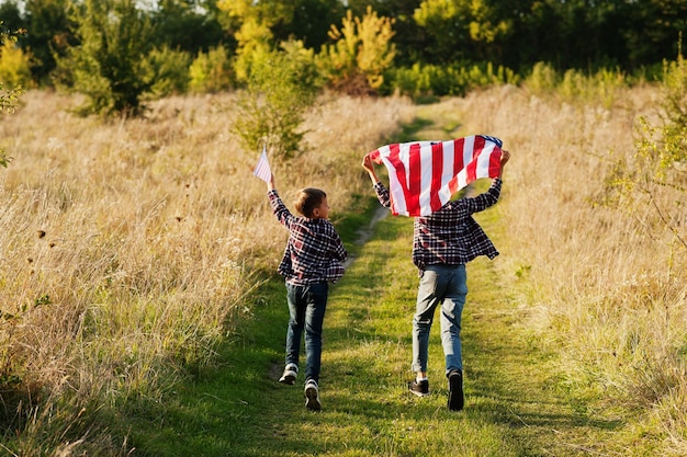 Zwei Brüder, die mit USA-Flagge laufen Amerika-Feiertag Stolz darauf, Kinder des Landes zu sein