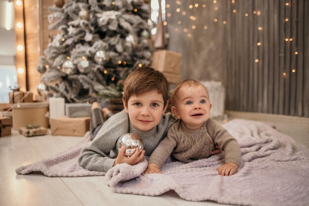 Zwei Brüder liegen auf einer Decke in einem Zimmer neben dem Weihnachtsbaum