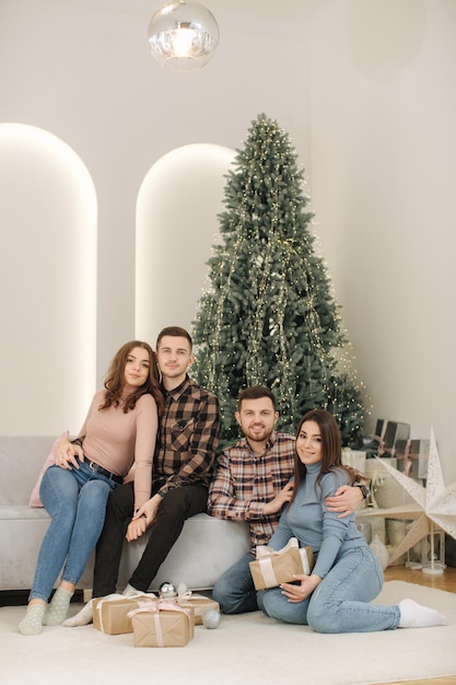 Zwei Brüder mit ihren Ehefrauen bei der Neujahrsfotosession schöne Frau und Mann vor Tannenbaum