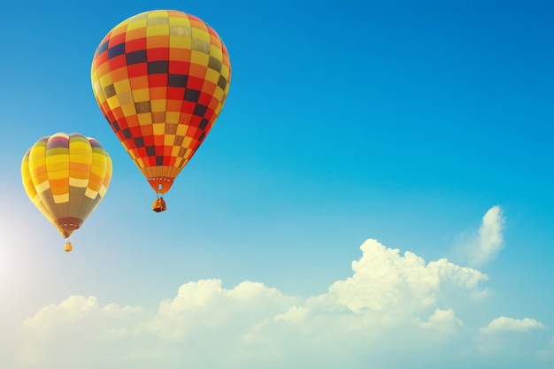 Zwei bunte Heißluft steigt oben im blauen Himmel mit Wolke im Ballon auf. Reise-Hintergrund-Konzept.