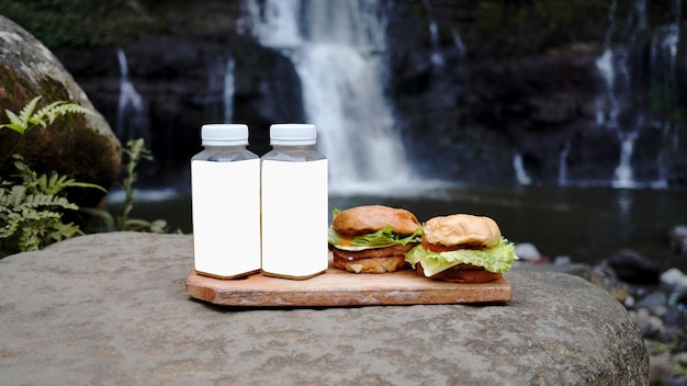 zwei Burger und zwei Getränkeflaschen mit einem sehr coolen Wasserfallhintergrund