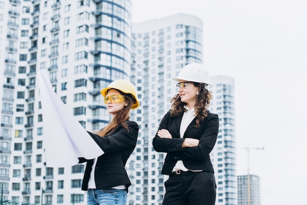 Zwei Business-Frauen in Schutzhelme und Schutzbrille Blick auf Gebäude-Systeme, architektonisches Konzept