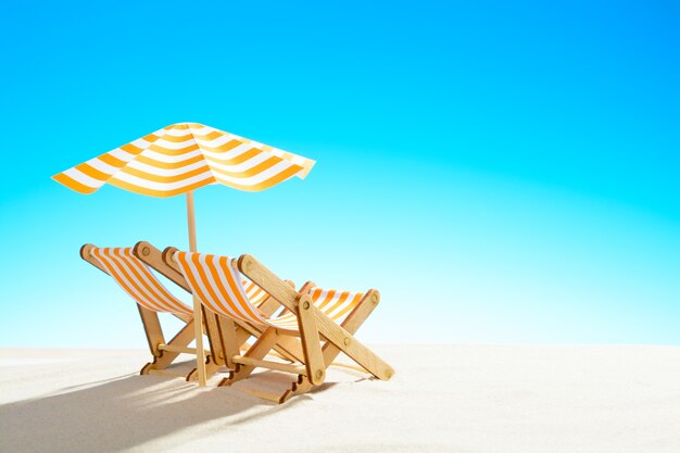 Zwei Chaiselongue unter einem Regenschirm am Sandstrand, Himmel mit Kopierraum