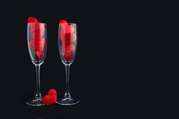 Zwei Champagnergläser mit roten Herzen für Paar. Fröhliches Abendessen zum Valentinstag.