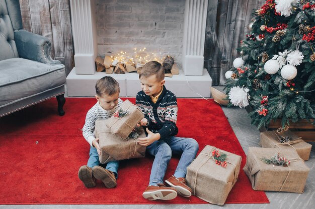 Zwei charmante Jungen öffnen Weihnachtsgeschenkbox