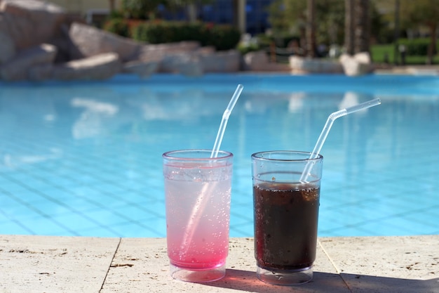 Zwei Cocktailgläser durch ein blaues Wasser des Swimmingpools Sommerurlaub