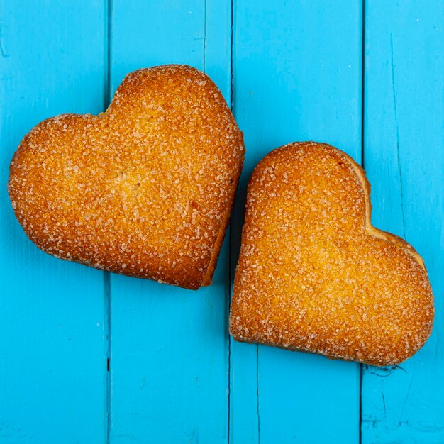 Zwei Cookie-Herzen auf blauem Hintergrund aus Holz. Valentinstag.