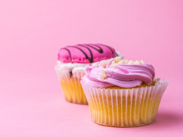 Zwei Cupcakes mit Fruchtfüllung auf rosa Oberfläche