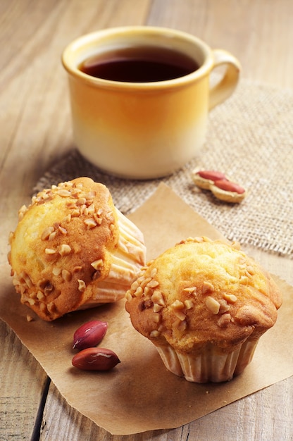 Zwei Cupcakes mit Nüssen und Tee auf Holztisch