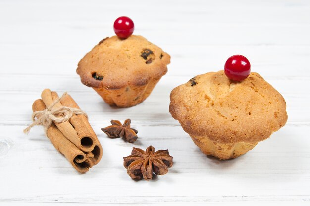 Zwei Cupcakes mit rotem Kirschzimt und Sternanis auf einem weißen Holztisch