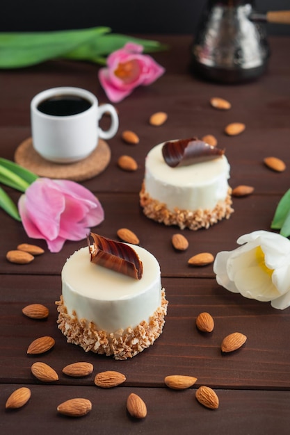 Zwei Cupcakes mit schokoladenweißer Kaffeetasse Mandeln und Tulpen auf Holztisch Selektiver Fokus