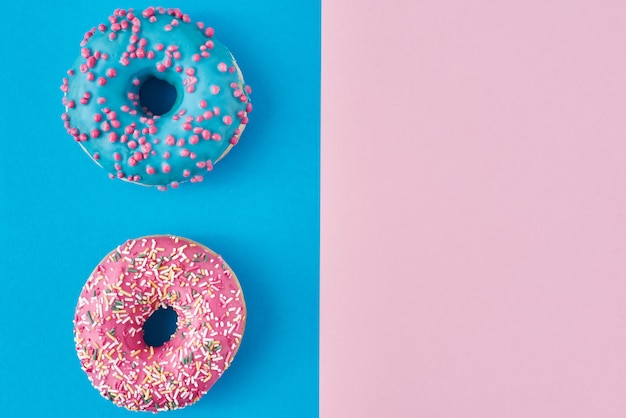 Zwei Donuts auf Pastellrosa und Blau. Minimalismus kreative Lebensmittelkomposition. Flacher Laienstil