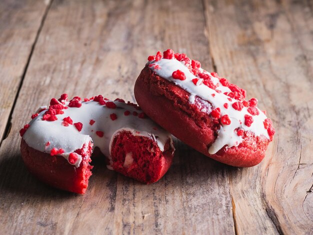 Zwei Donuts, einer auf Holzhintergrund gebissen