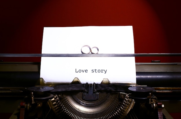 Zwei Eheringe im Unendlichkeitszeichen auf einer Schreibmaschine. Konzept der Eheversprechen.