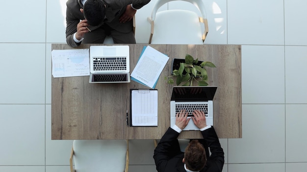 Zwei erfolgreiche lächelnde Geschäftsleute arbeiten an einer Laptop-Ansicht von oben