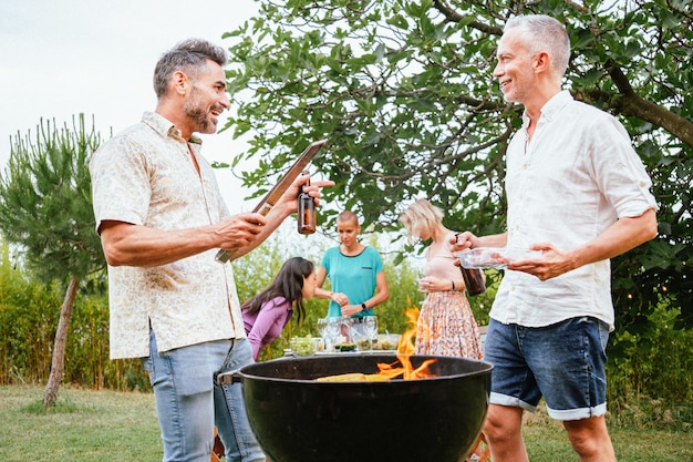 Zwei erwachsene Freunde oder Familienväter unterhalten sich und lächeln beim Kochen und Grillen bei einer Grillparty