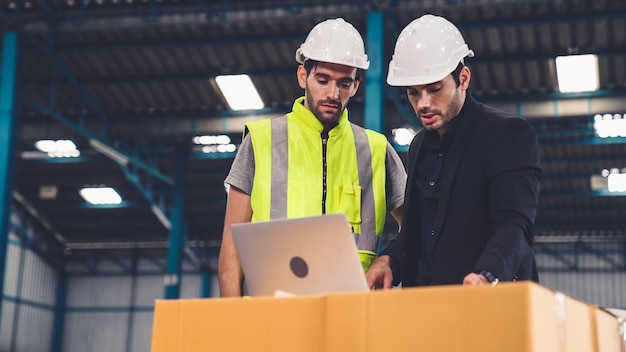 Zwei Fabrikarbeiter arbeiten und besprechen den Fertigungsplan in der Fabrik