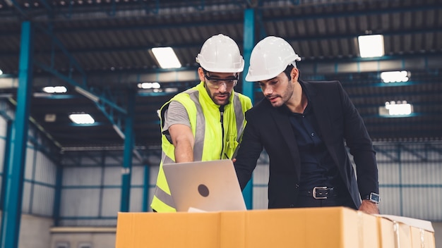 Zwei Fabrikarbeiter arbeiten und besprechen den Fertigungsplan in der Fabrik.