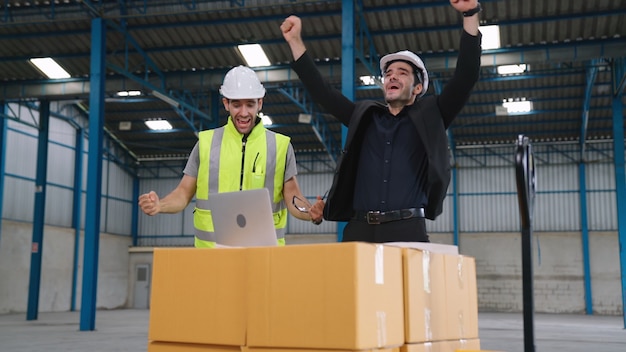 Zwei Fabrikarbeiter feiern gemeinsam Erfolge in der Fabrik oder im Lager. Arbeitsleistungskonzept der Industrie.